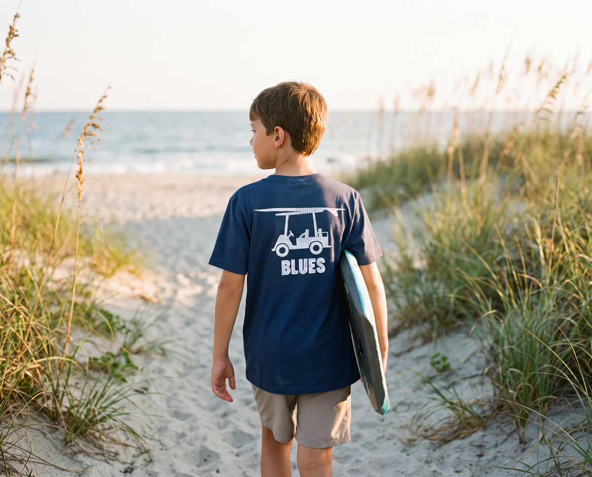 Boy on a dune path in the Bald Head Blues youth Island Tee in Navy with the cart and Blues back print